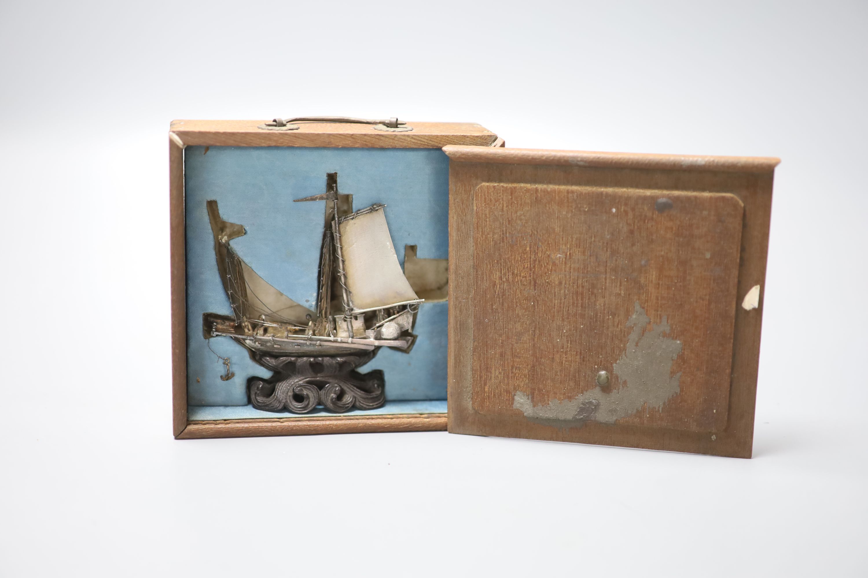 A Chinese white metal miniature model of a junk, 75mm, on wooden stand, in fitted box.